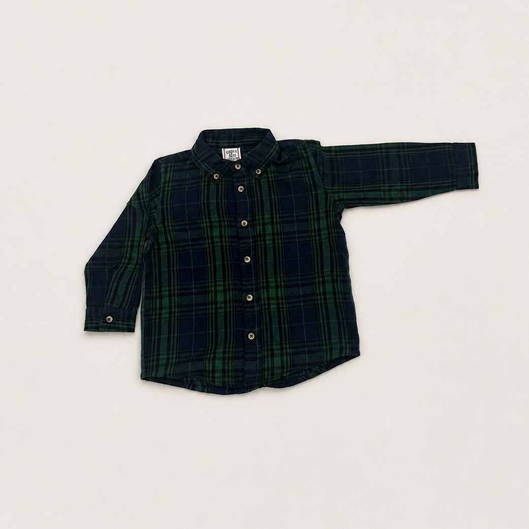A long-sleeve button-down shirt in a dark green and navy plaid pattern, laid flat on a light beige background.