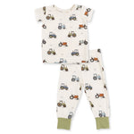 A two-piece baby pajama set featuring a short-sleeve top and matching pants. The pajamas are off-white with an all-over tractor pattern in blue, green, and orange, finished with solid sage green cuffs.