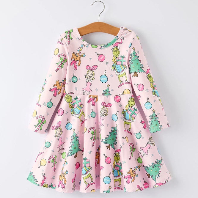 A pink long-sleeve dress with a colorful Christmas-themed print featuring the Grinch, Cindy Lou, Max the Dog, and Christmas decorations hanging on a wooden hanger against a light gray background.