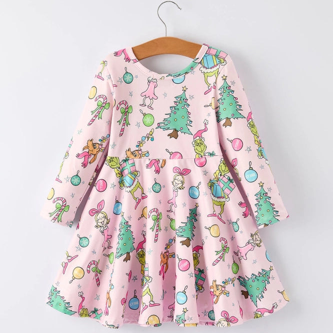 A pink long-sleeve dress with a colorful cartoon Grinch print, hanging on a wooden hanger against a light gray background.