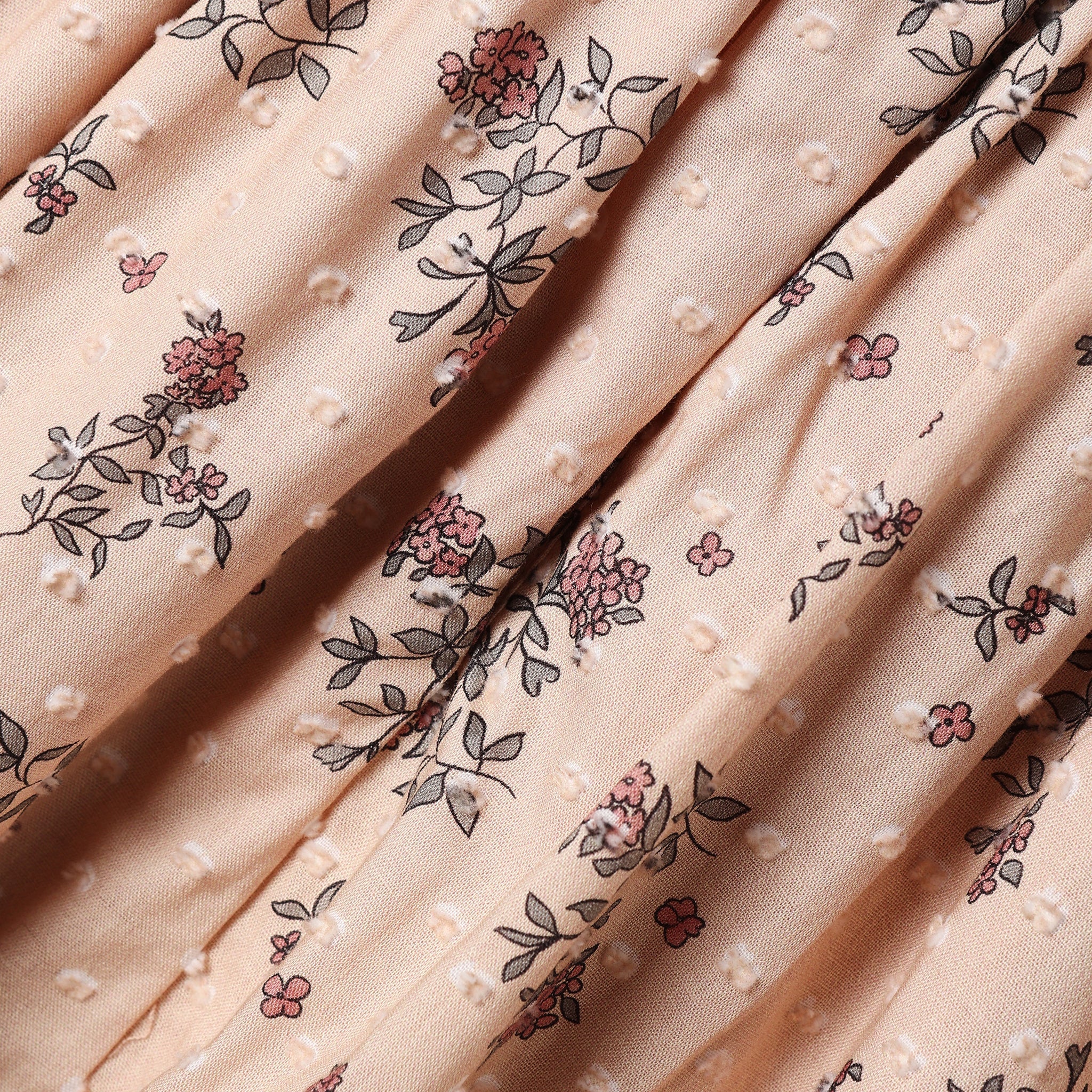 A close up of the fabric of the Maddie Dress from Noralee, showing the swiss dot texture and floral pattern. 