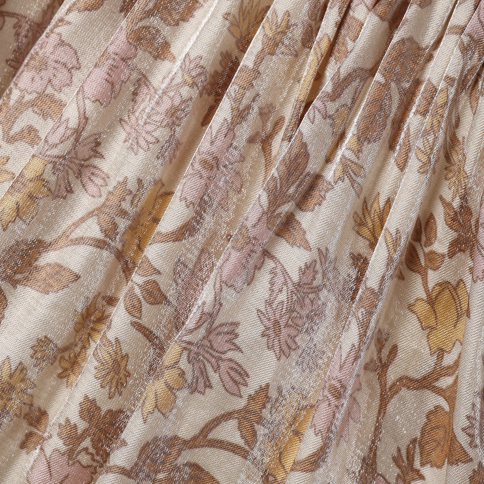 A close-up of a pleated fabric with a floral pattern in dusty pink, mustard yellow, and brown on a warm beige background.