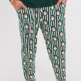 A person wearing dark green pajama pants with a vertical white stripe pattern and a repeating Santa Claus face motif, paired with a dark green long-sleeve top. The photo is cropped from the chest down against a plain white studio background.