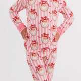 A child wearing a pink and white striped long-sleeve pajama set with a red Santa Claus face print, standing against a light gray studio background.