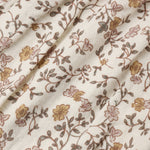 A close-up of a cream-colored fabric with a delicate floral vine pattern in muted brown, dusty pink, and mustard yellow.