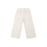 A pair of wide-leg pants in a warm off-white or cream base fabric with a dense, small-scale floral print in muted green and gray tones, shown flat against a solid white background.