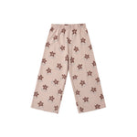 A pair of children's wide-leg pants in a light beige or dusty pink color, featuring an all-over brown flower pattern, displayed flat against a solid white background.