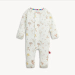 A baby long-sleeve footless one-piece romper in off-white, decorated with a whimsical woodland print of trees, birds, flowers, and stars. The romper features a colorful striped inner collar and a small red tag on the lower leg, shown against a plain light background.