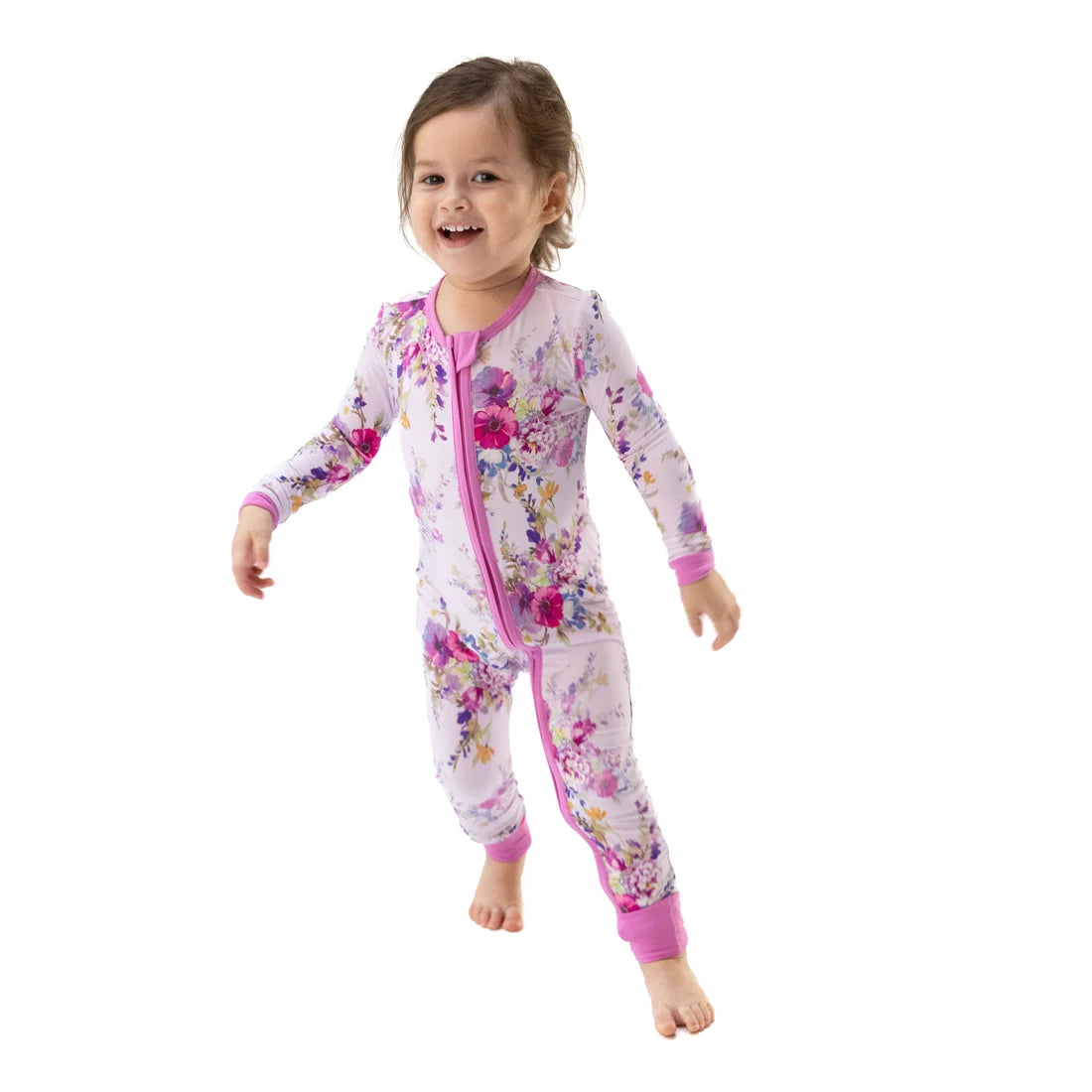 A toddler girl models a convertible romper in a soft lilac with a floral print all over. 