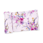 A folded blanket, featuring a colorful watercolor floral pattern with pink, purple, blue, and green tones, set against a plain white background.