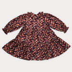 A long-sleeve baby dress with a ruffled collar and a dense floral print, laid flat on a light gray background.