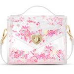 A clear vinyl handbag filled with tiny peppermint and gingerbread house confetti, a gold heart-shaped clasp, and a clear handle, shown on a white background.