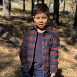Child wearing a plaid shirt in a forest setting