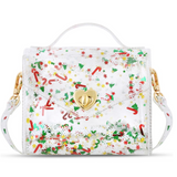 A clear plastic handbag with a festive Christmas print of candy canes, holly, pine trees, and snowflakes, featuring a gold heart-shaped clasp and a white top handle.