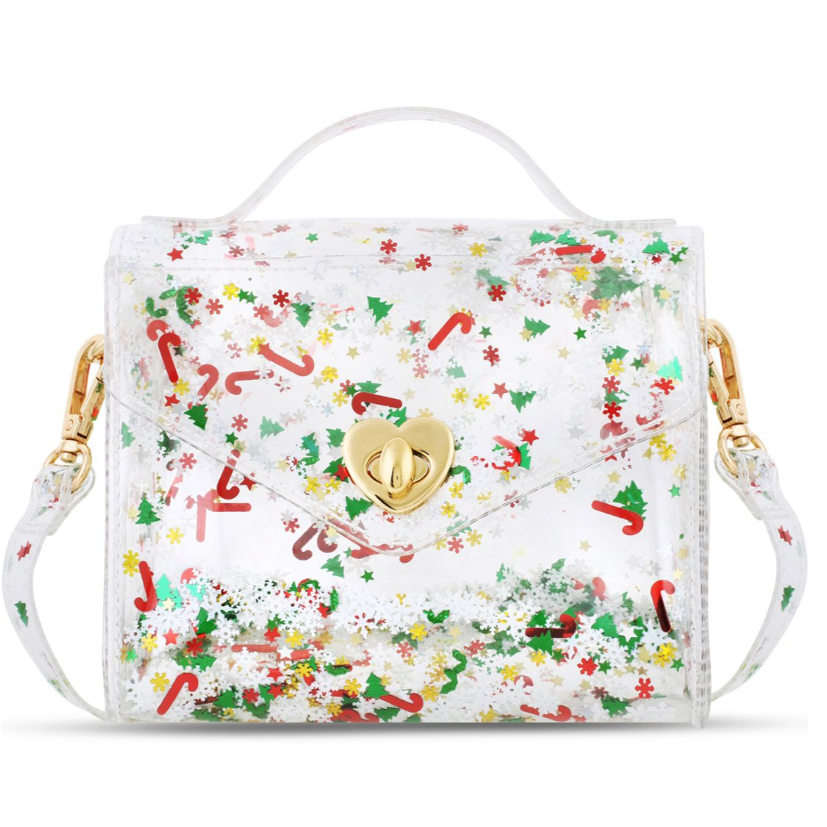 A clear plastic handbag with a festive Christmas print of candy canes, holly, pine trees, and snowflakes, featuring a gold heart-shaped clasp and a white top handle.