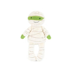 A plush mummy doll wrapped in cream-colored fabric bandages with bright green accents on the eyes, hands, and feet, set against a plain white background.