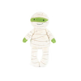 A plush mummy doll wrapped in cream-colored fabric bandages with bright green accents on the eyes, hands, and feet, set against a plain white background.