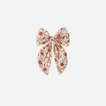 A pink floral hair bow atop a white background. 