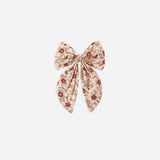 A pink floral hair bow atop a white background. 