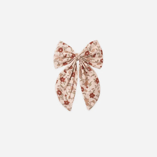 A pink floral hair bow atop a white background. 