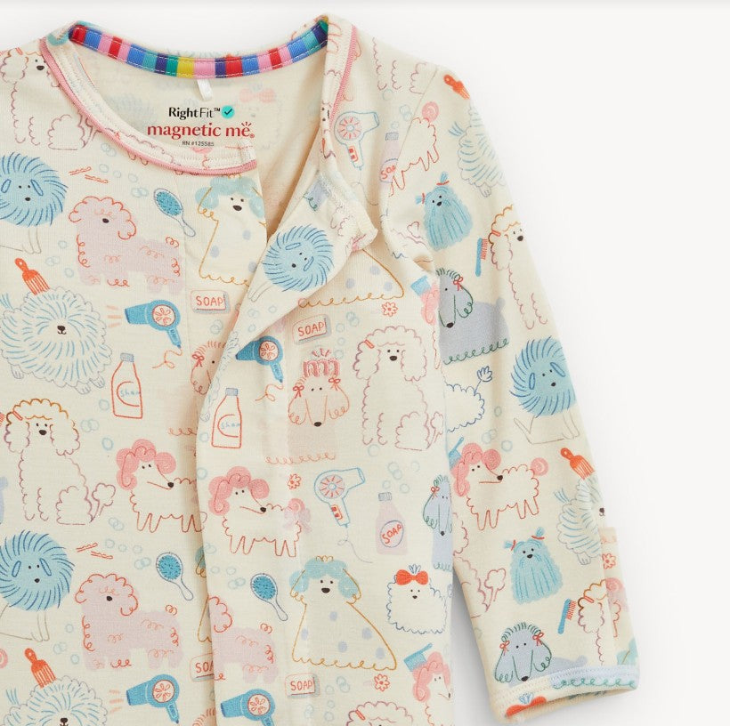 A baby long-sleeve pajama top with a playful cartoon print of sheep, lions, and other animals in pastel colors on a cream background. The brand name 'magnetic me.