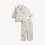 A two-piece children's pajama set featuring a long-sleeve button-up top and matching pants, both printed with a whimsical cartoon pattern in light blue, pink, and yellow on a cream background.