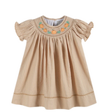 A beige baby girl's dress with vertical stripes, ruffled short sleeves, and a smocked neckline decorated with embroidered orange pumpkins and green leaves, shown on a plain white background.